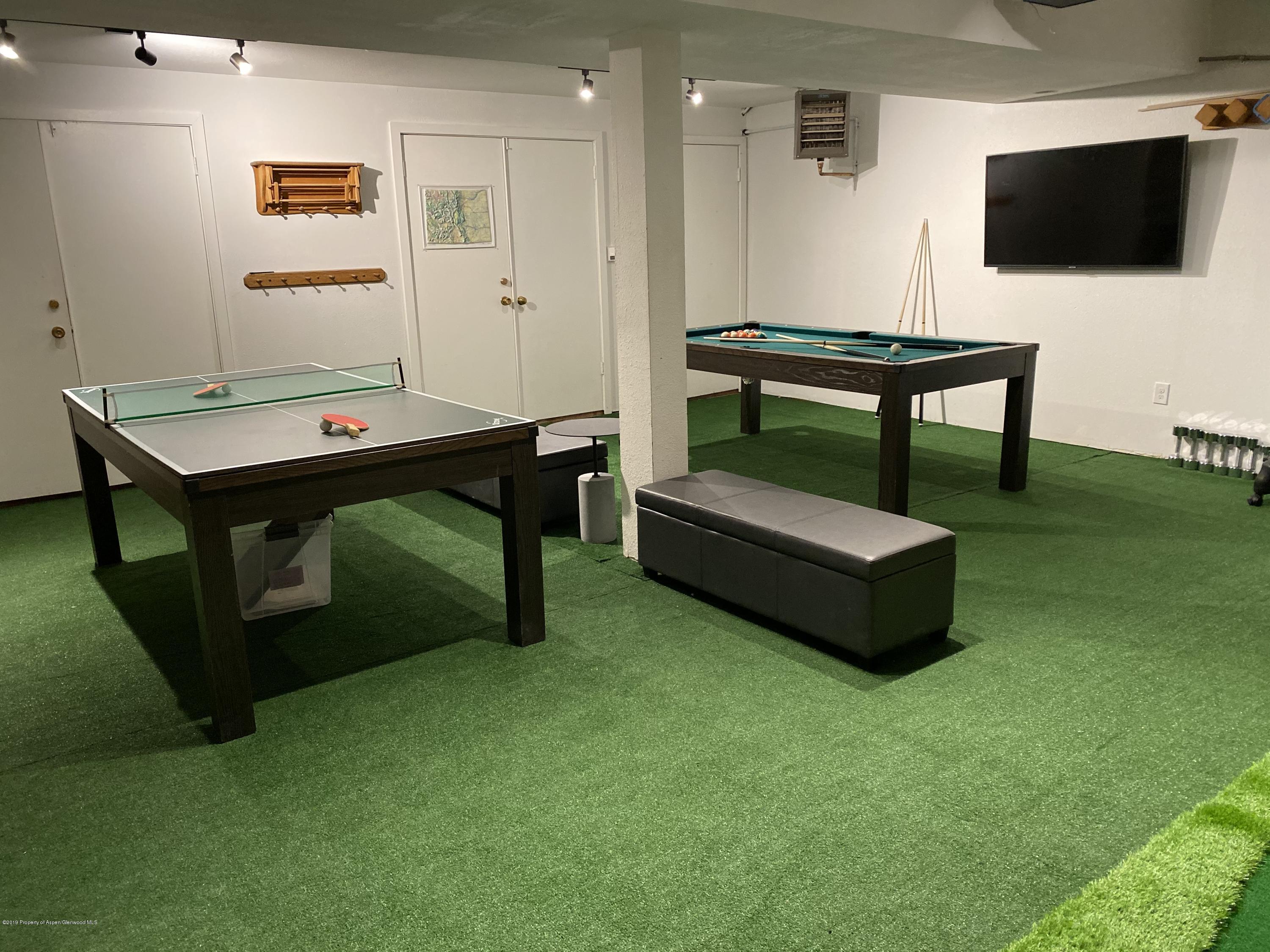 Recreation room with ping-pong and pool tables on green turf flooring.