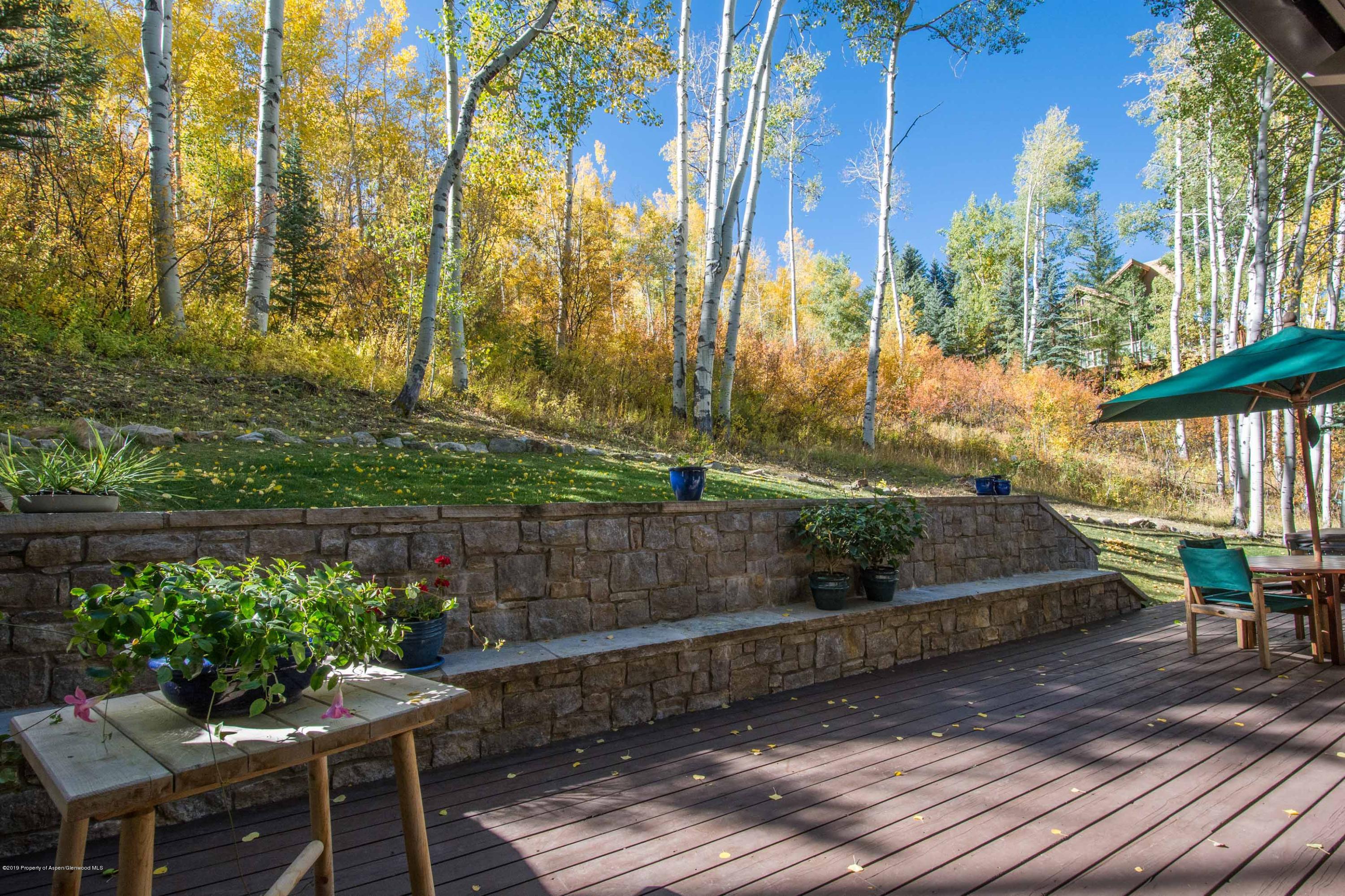 Wood deck and stone patio terrace overlooking a hillside of golden aspens.