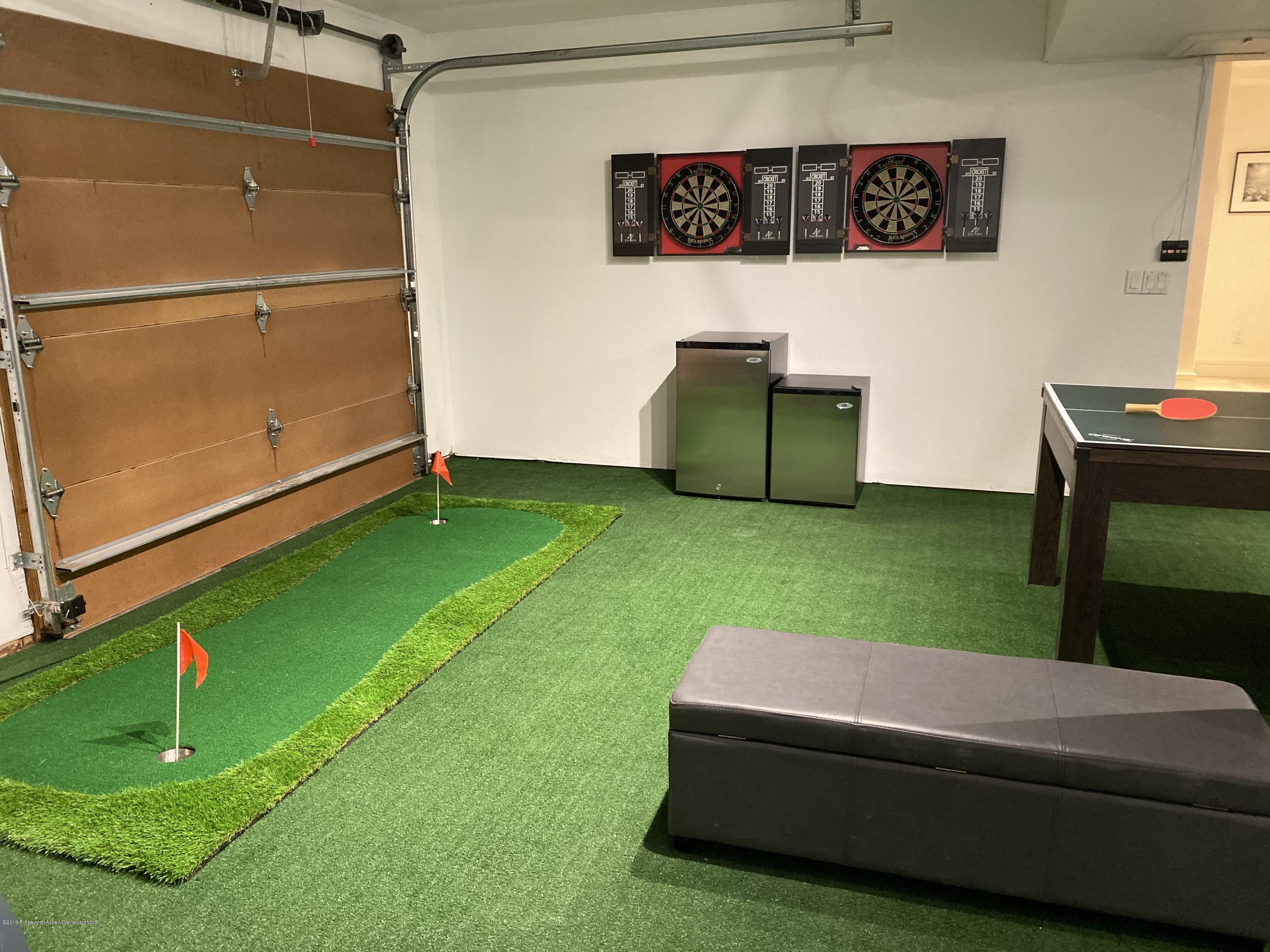 Recreation room with an indoor putting green, dartboards, and a ping-pong table.