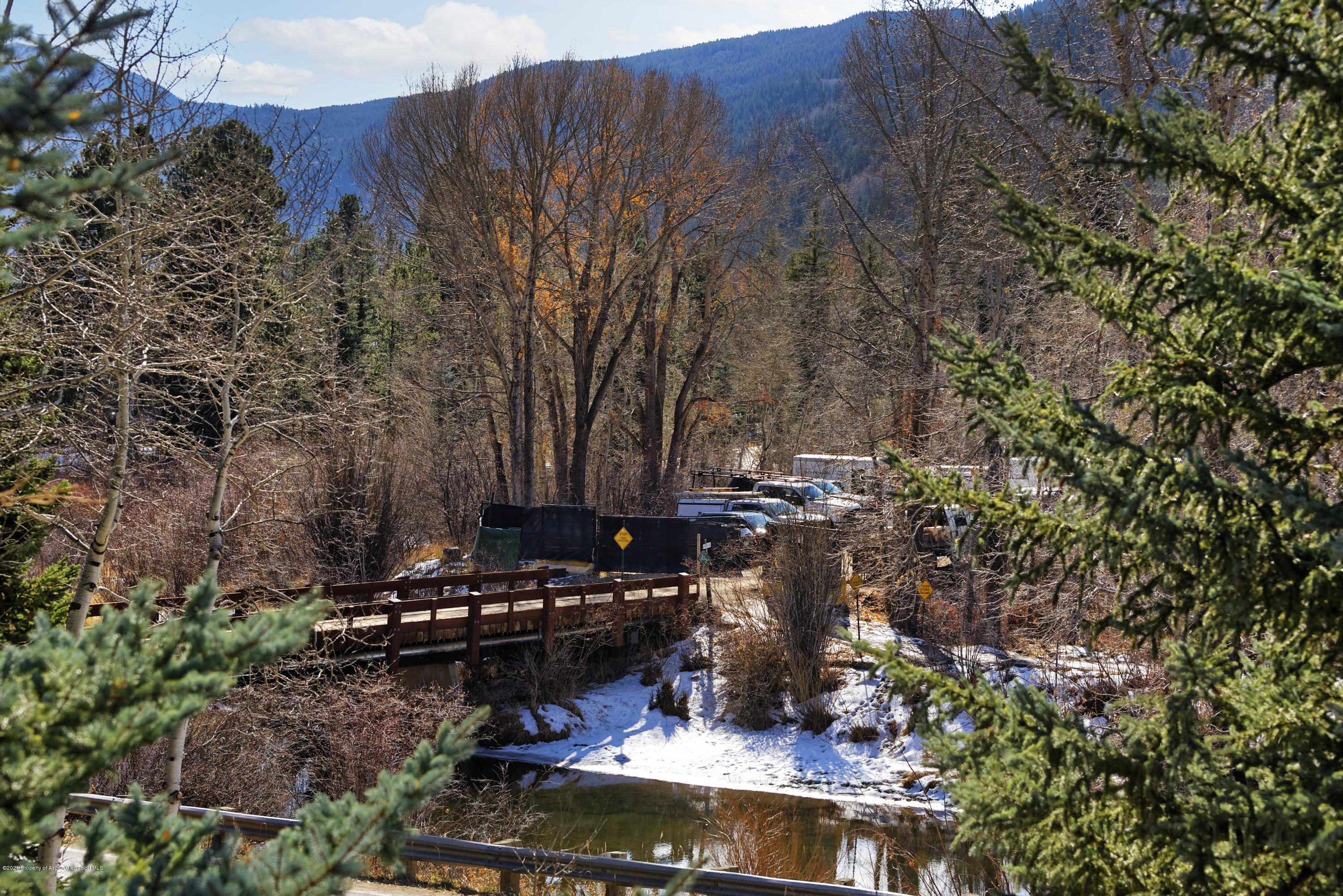Creek and wooden bridge in a snowy, wooded mountain setting.