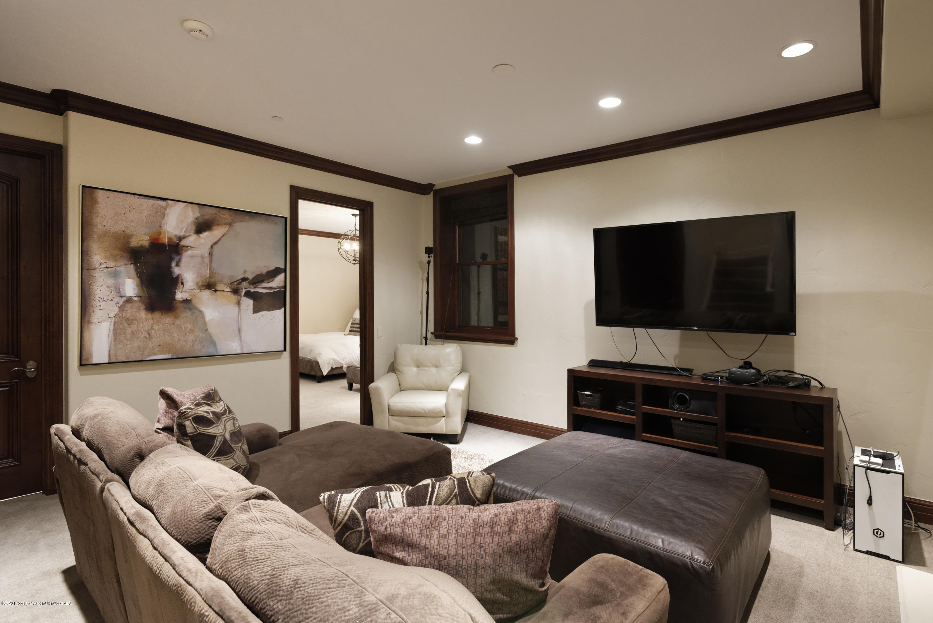 Furnished living room with a wall-mounted TV, sectional sofa, and dark wood trim.