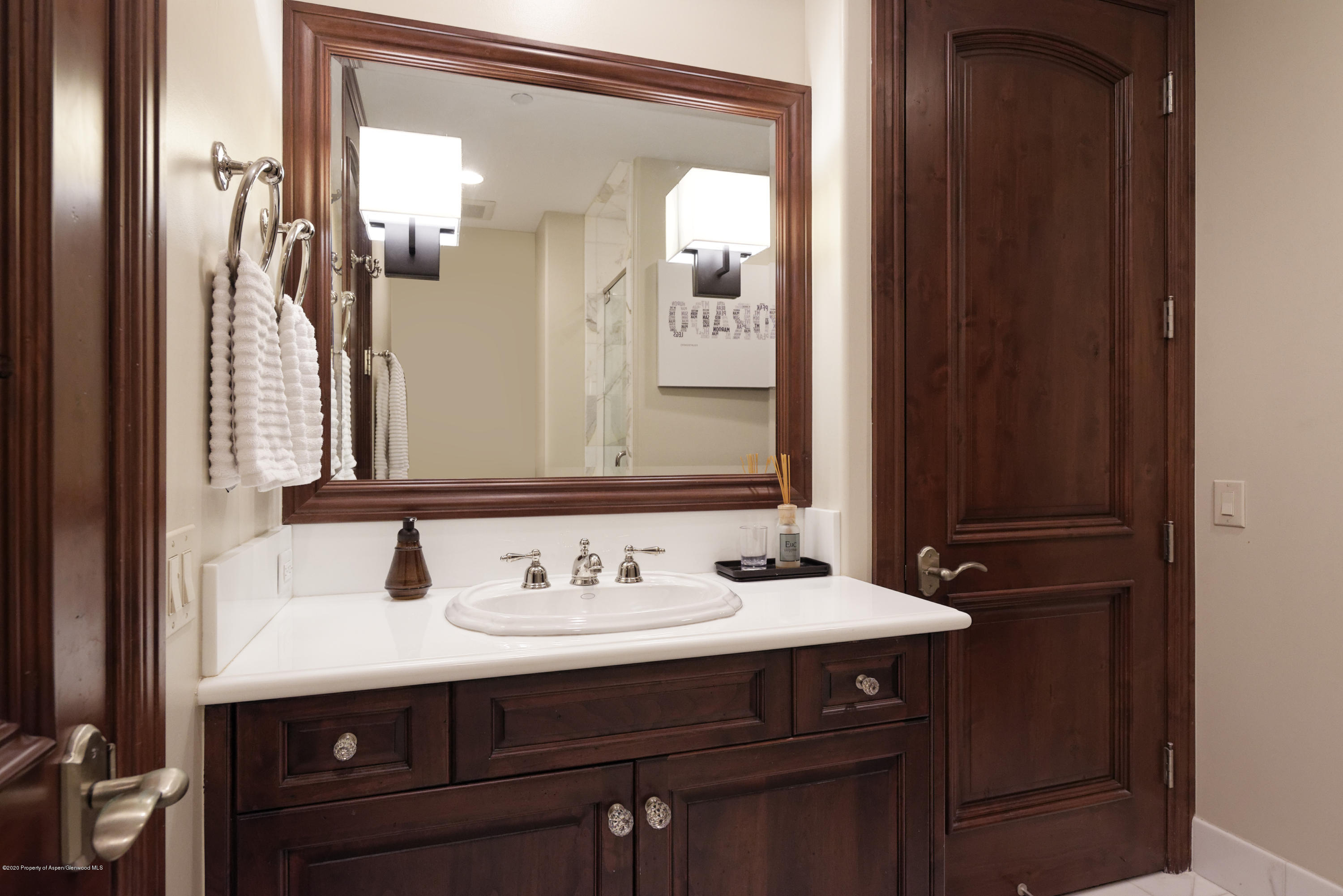 Bathroom vanity with dark wood cabinetry, a large framed mirror, and white towels.