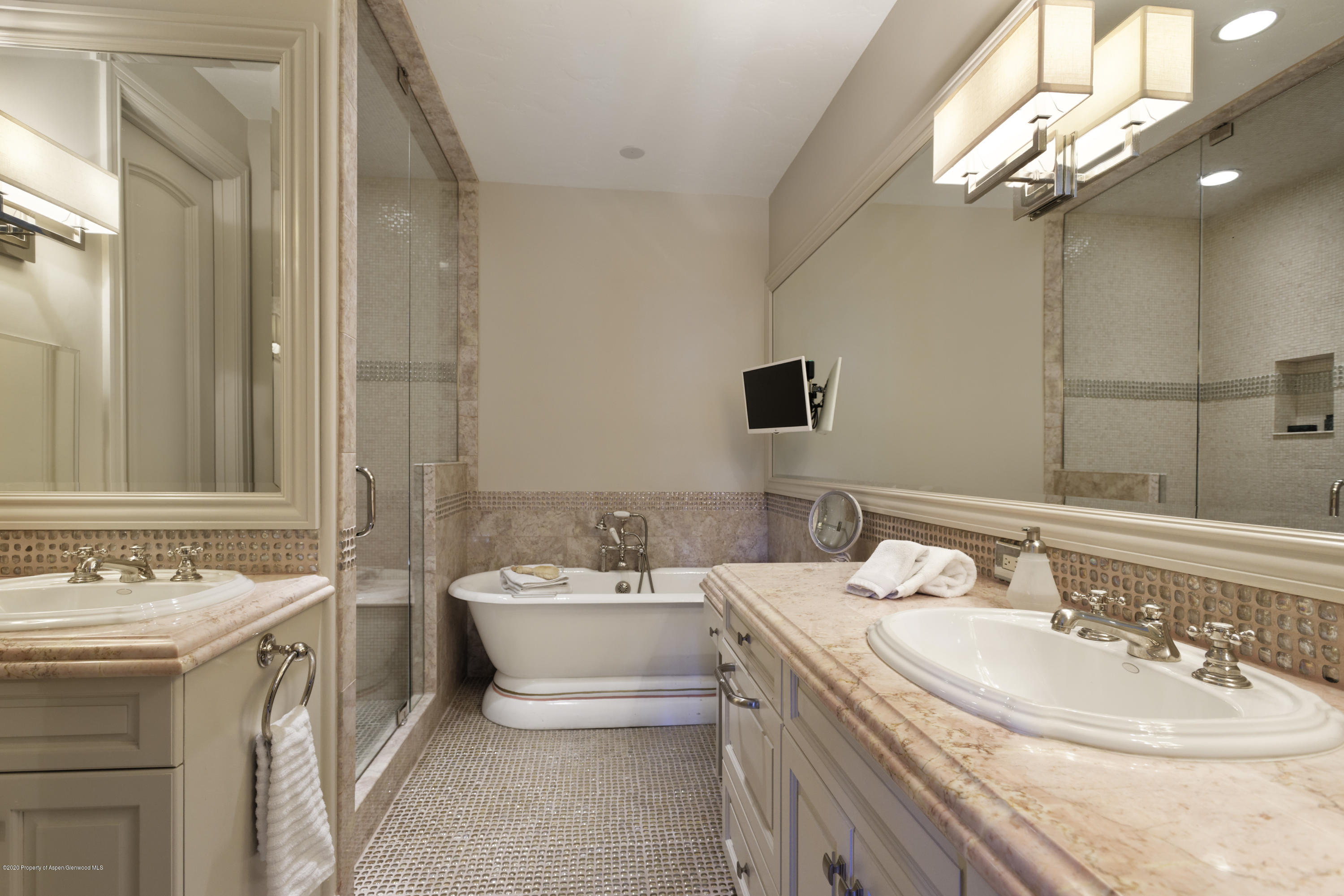 Bathroom with dual stone-counter vanities, a freestanding soaking tub, and a glass-enclosed shower.