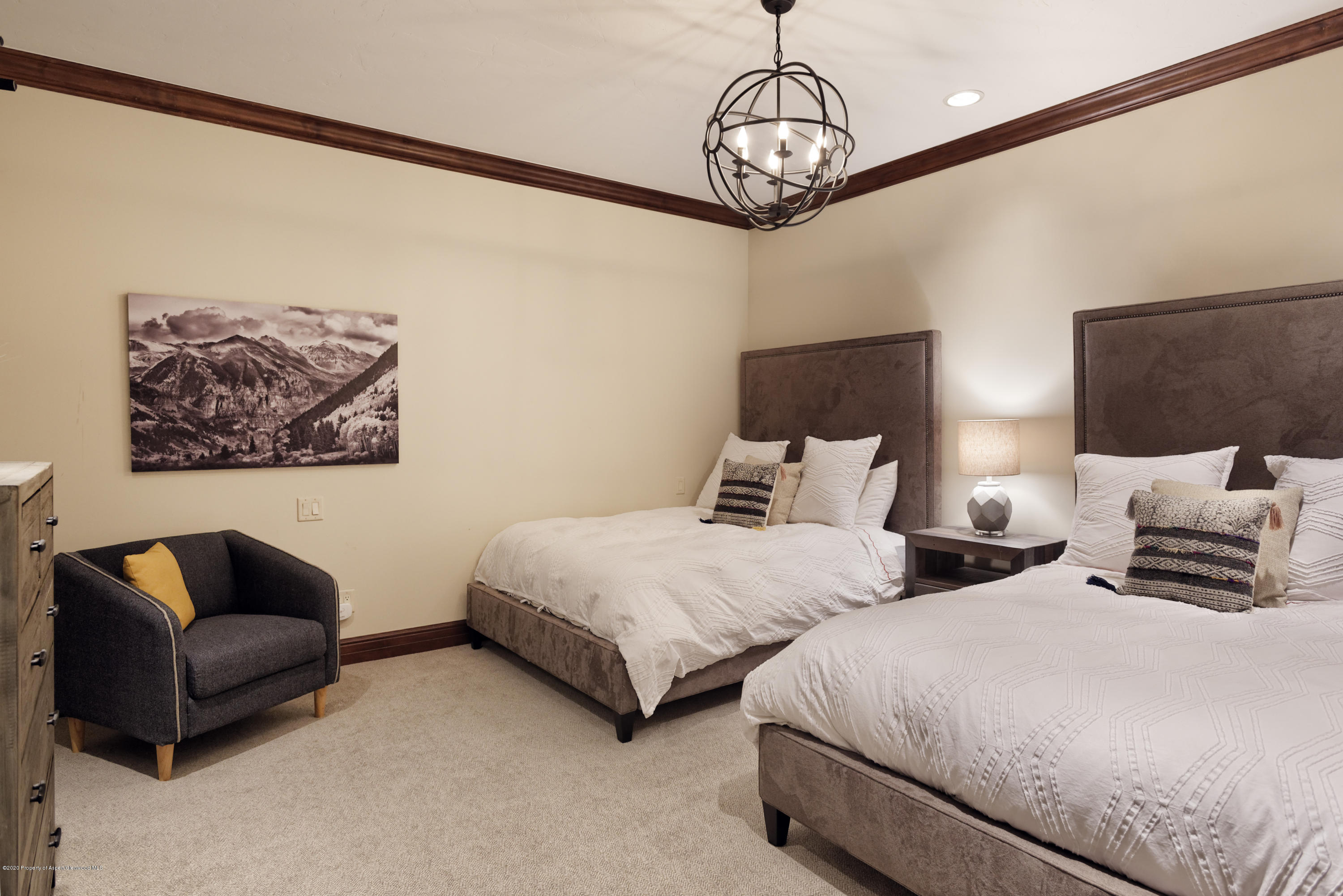 Bedroom with two beds, white bedding, upholstered headboards, and a dark armchair.