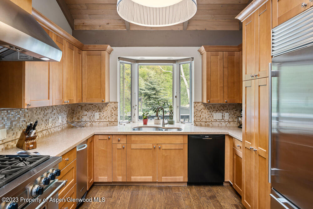 Kitchen with honey-toned cabinetry, a bay window over the sink, and stainless steel appliances.