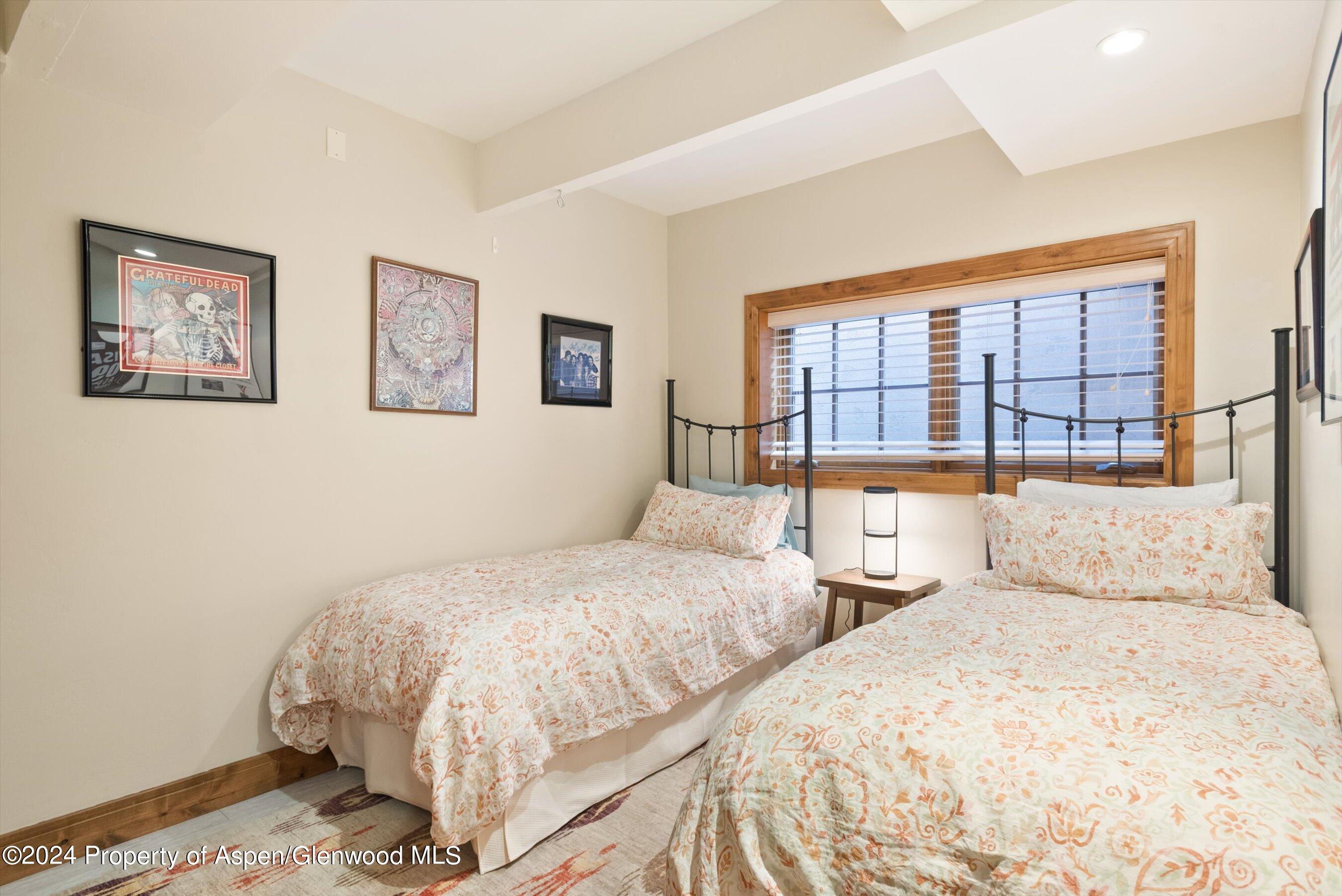 Bedroom with two floral-covered beds, black metal headboards, and a wood-trimmed window.