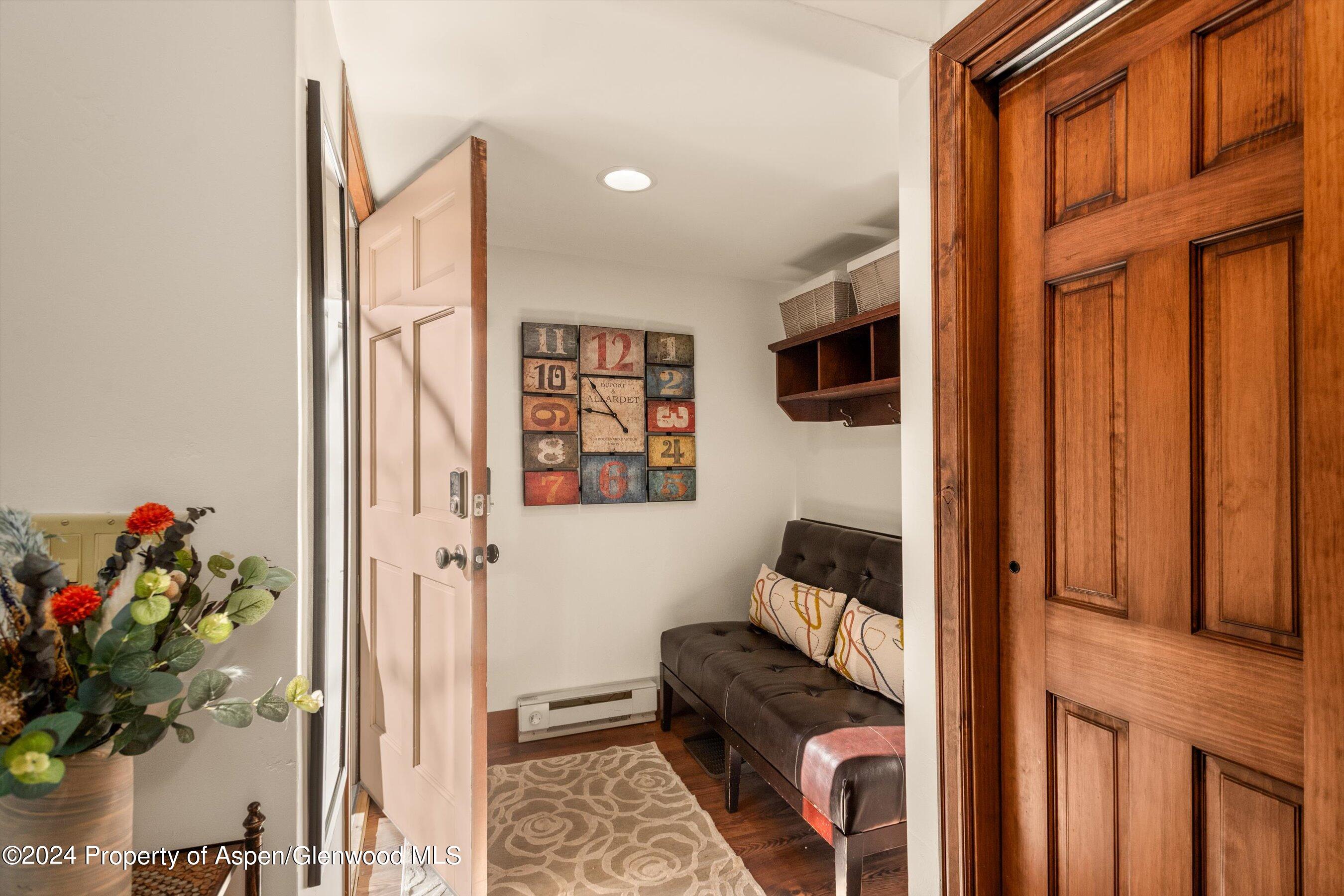 Furnished entryway with a dark bench, patterned rug, decorative clock, and prominent wood-trimmed doors.