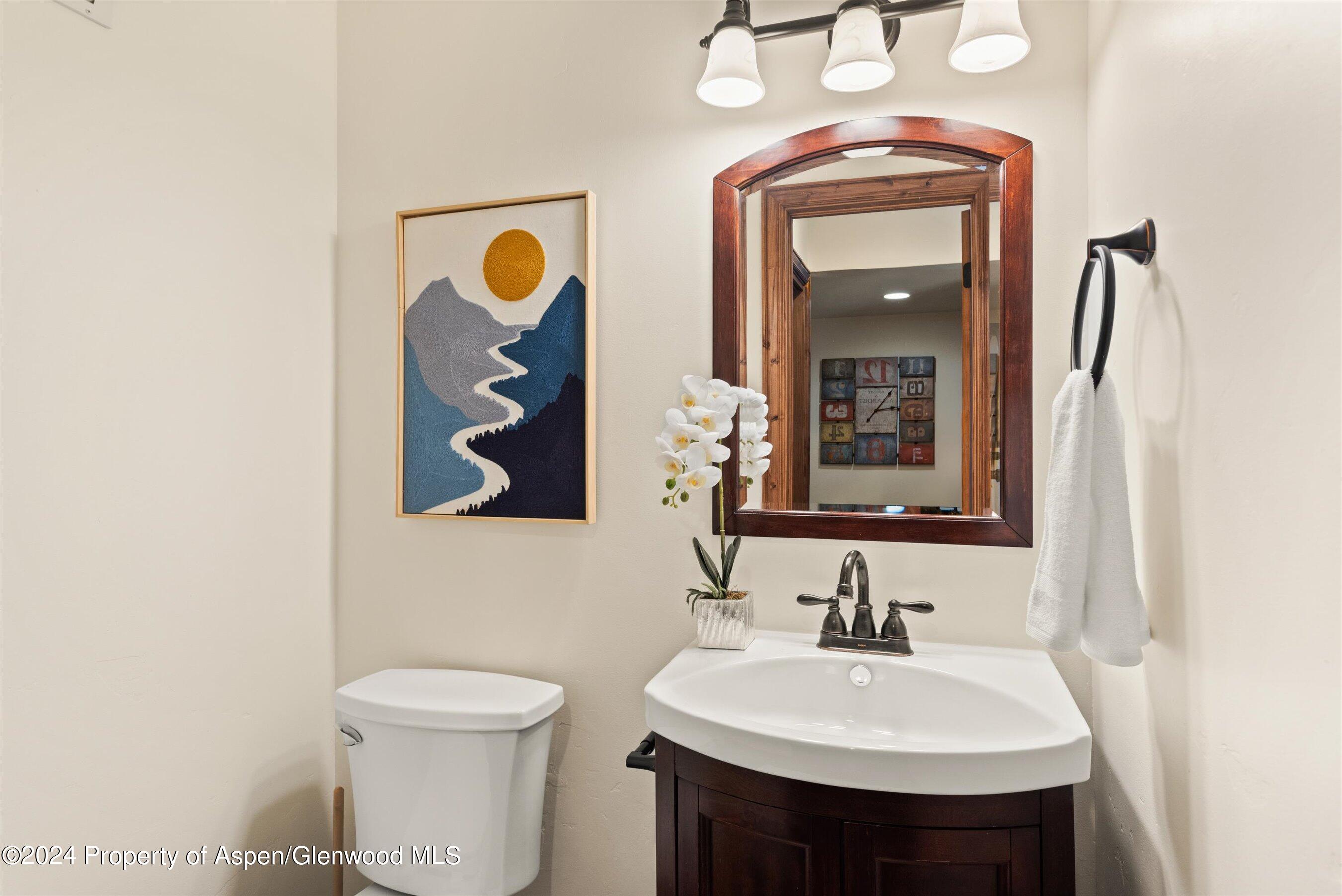Bathroom with a dark wood vanity, framed mirror, and mountain-themed artwork.