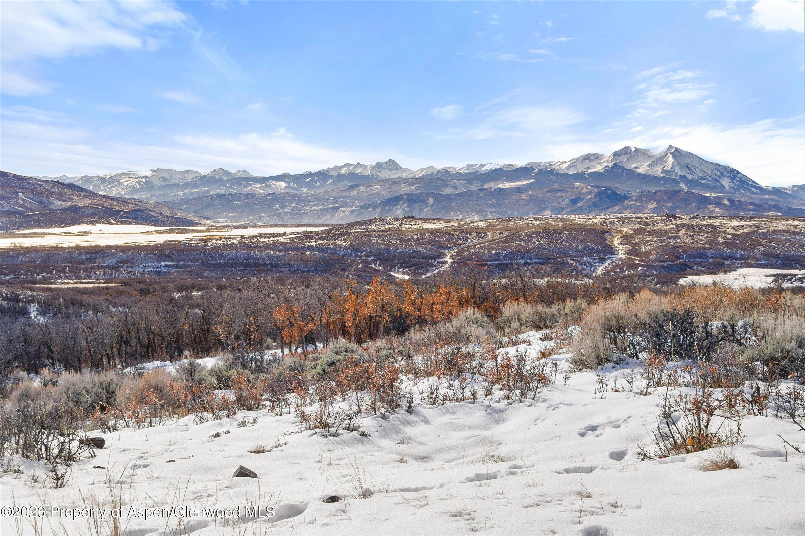 Snow-covered land with a panoramic view of distant snow-capped mountains.