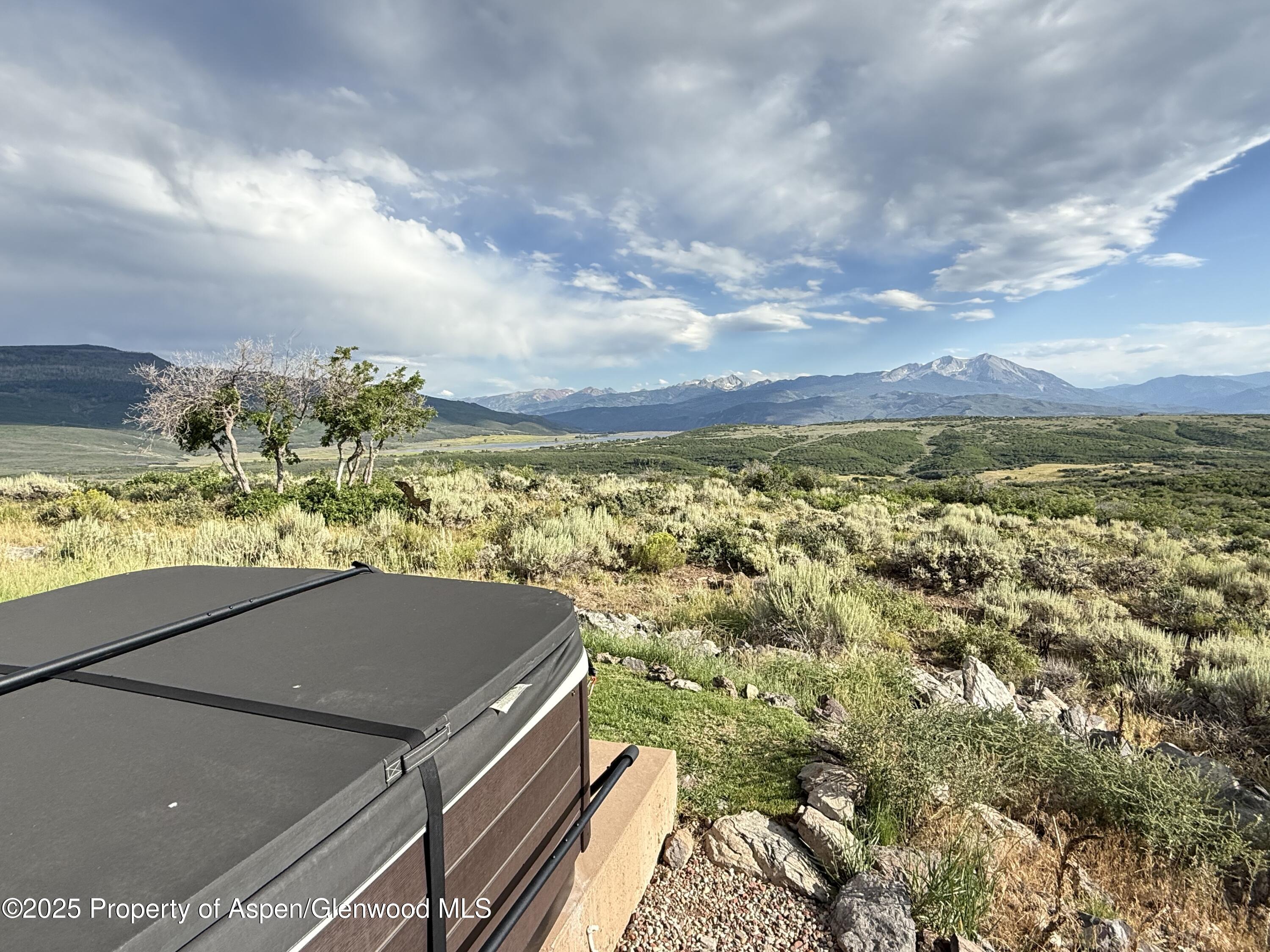 Mountain views across open high-country terrain, with a covered hot tub in the foreground.