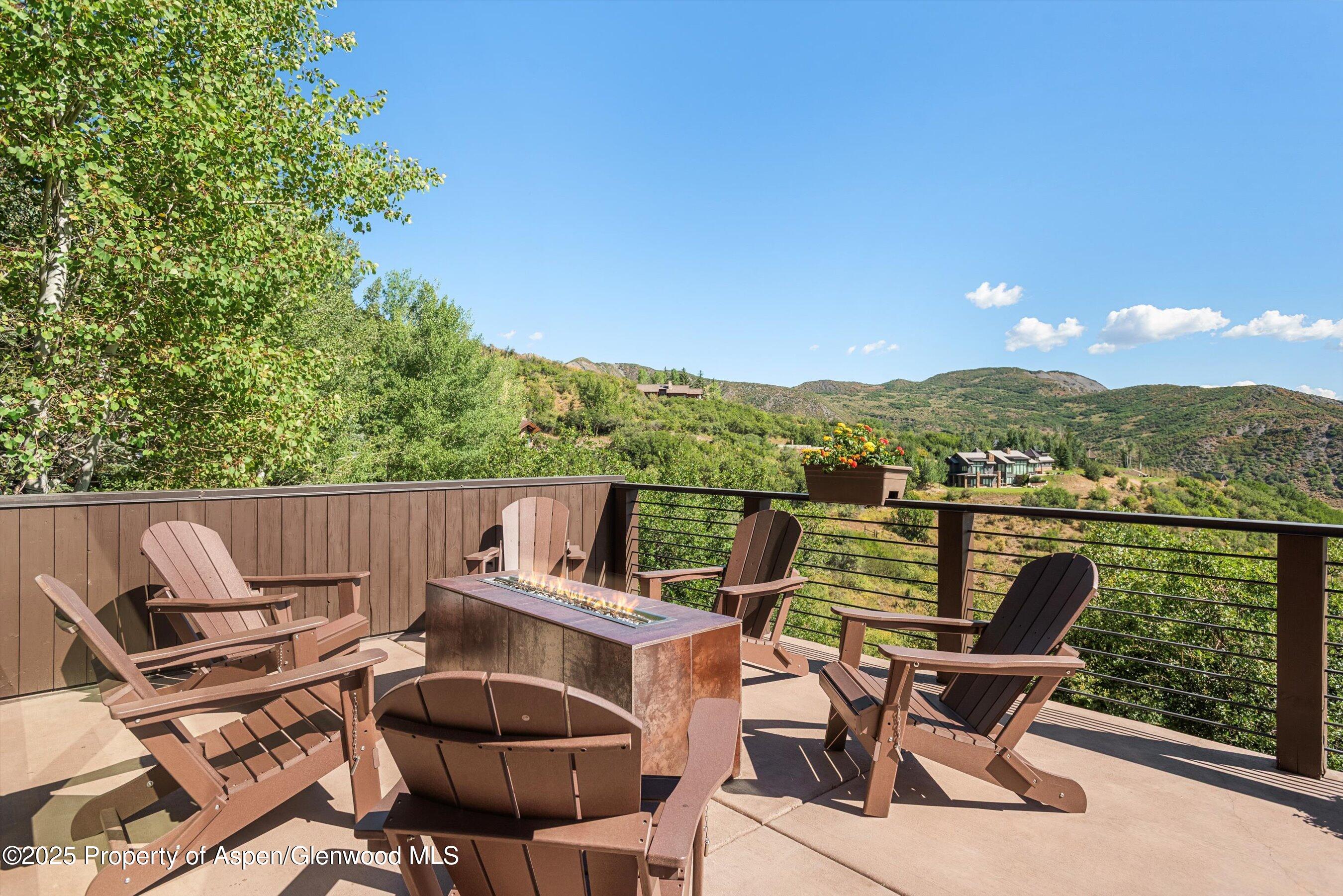 Mountain-view deck with Adirondack chairs around a gas fire pit.