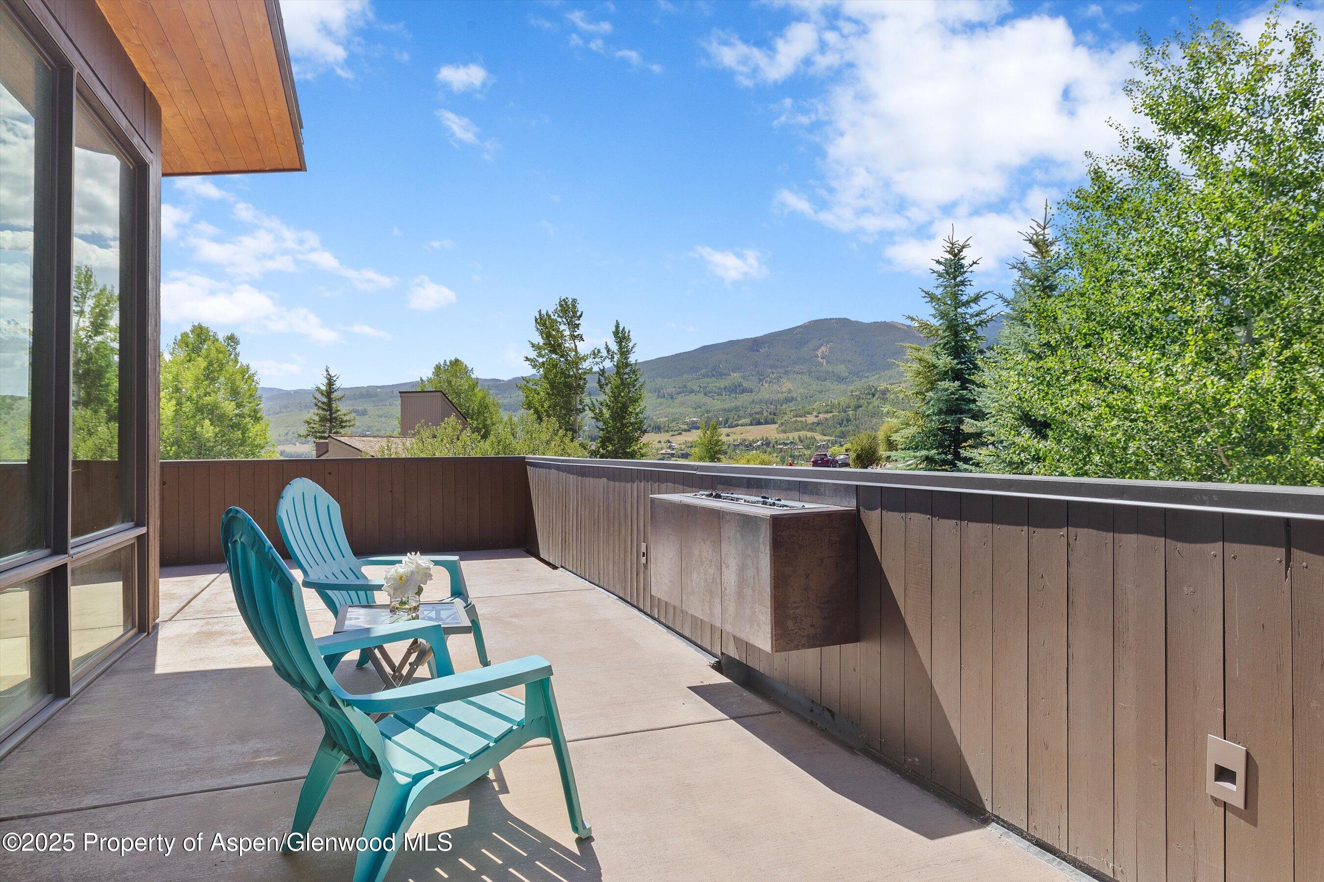 Mountain-view deck with turquoise Adirondack chairs and a built-in fire feature.