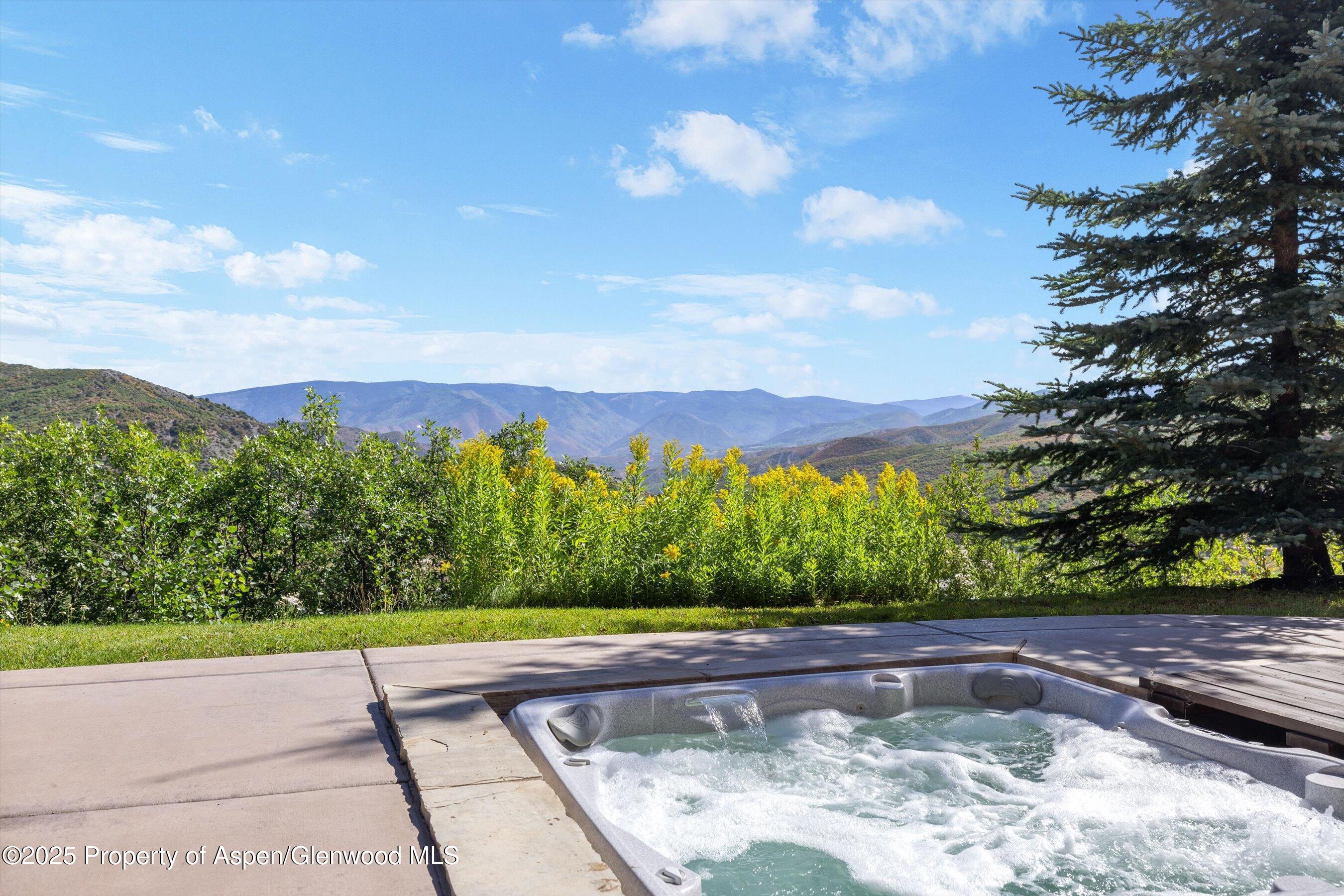 Outdoor hot tub on a patio overlooking wooded mountain ridges.