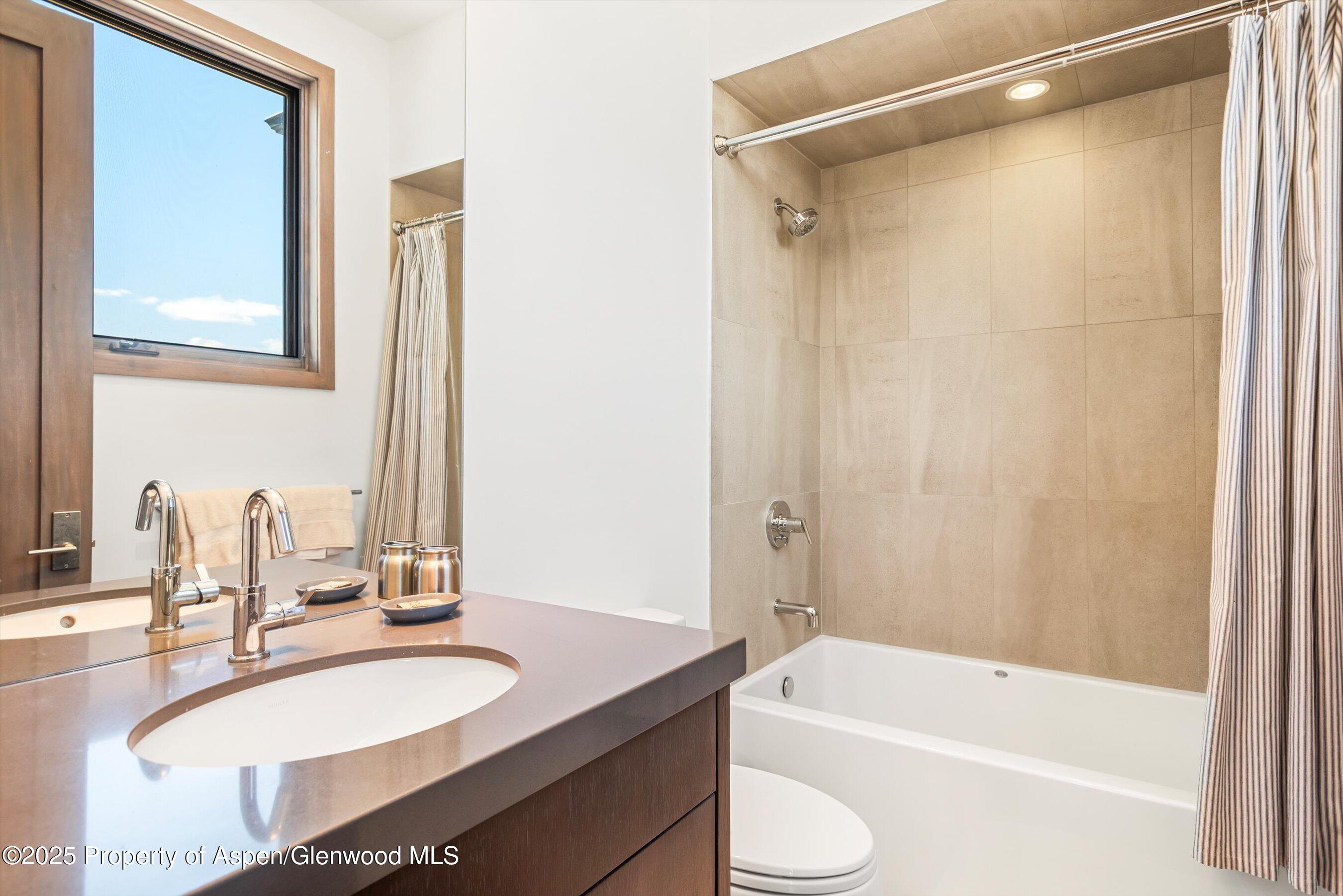 Bathroom with a dark wood vanity and sink beside a tiled tub and shower.