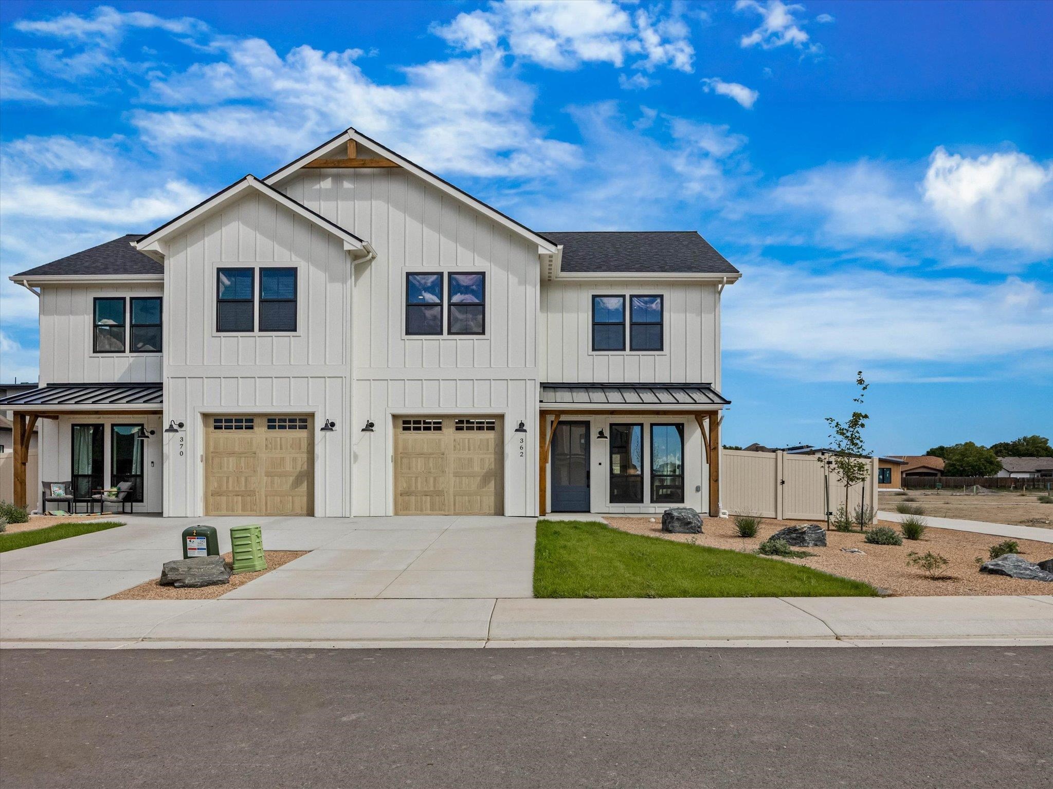 White two-story attached homes with wood garage doors, covered porches, and landscaped front yards.