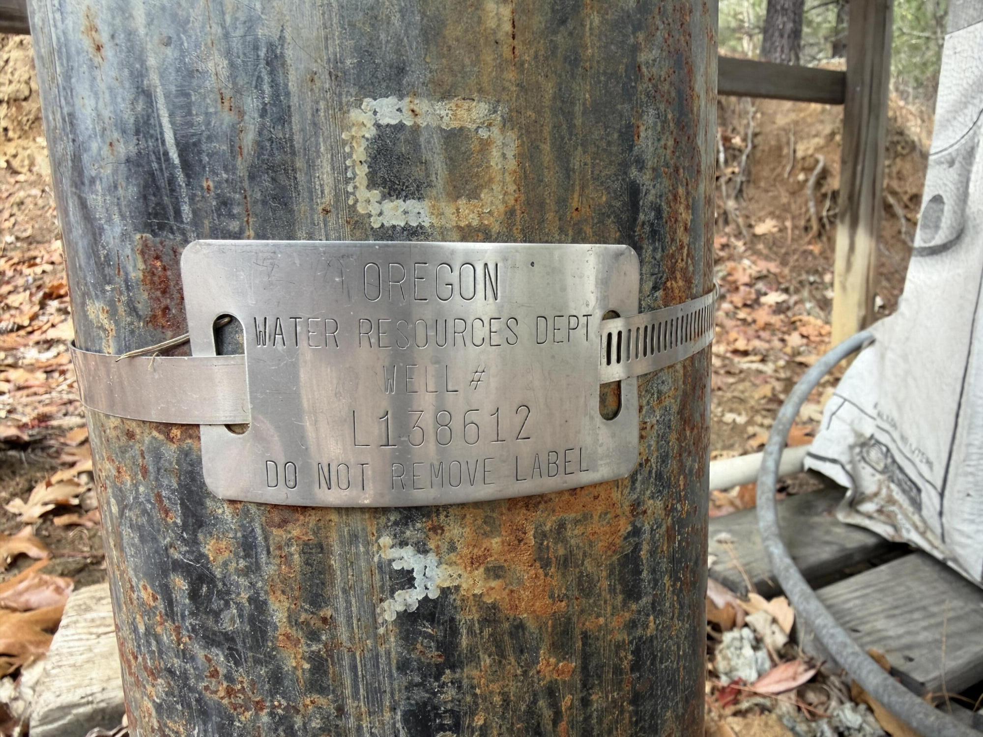Weathered well casing with an Oregon Water Resources Department plate marked L138612.