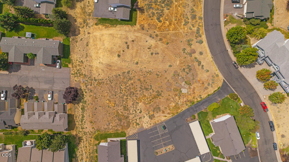 Undeveloped residential lot surrounded by homes, streets, and a parking area.