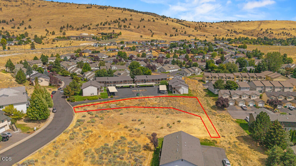 Vacant hillside parcel outlined in red above a residential neighborhood.