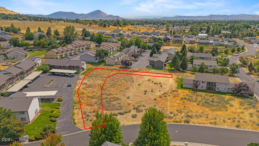 Vacant lot outlined in red in a residential neighborhood, with mountains in the distance.