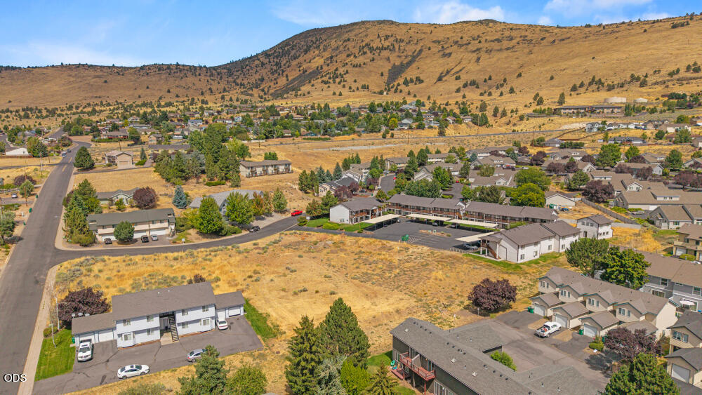 Aerial view of an open parcel among homes, with dry hills rising behind the neighborhood.