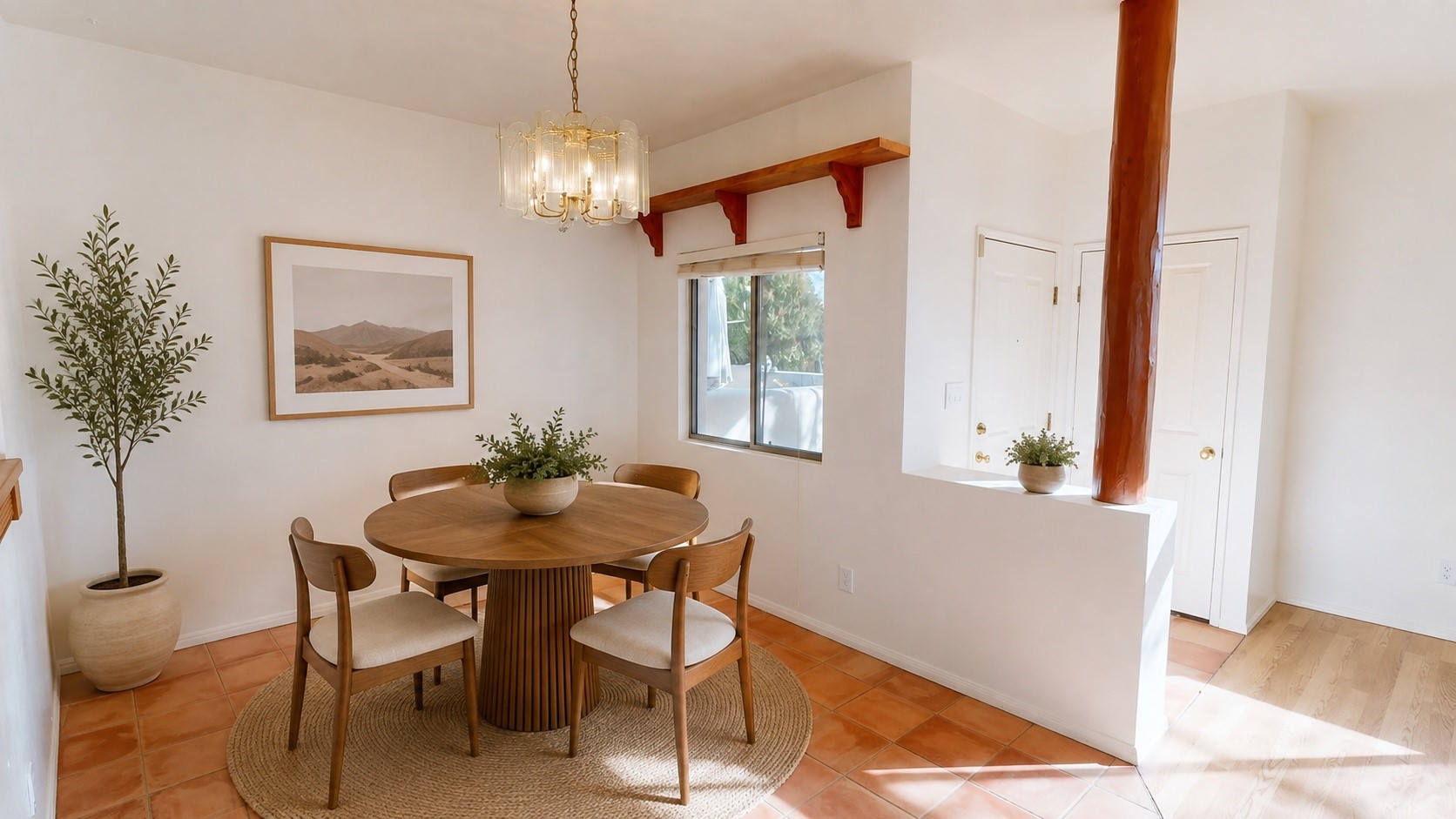 Dining room with a round wood table, woven rug, terracotta tile, and chandelier.