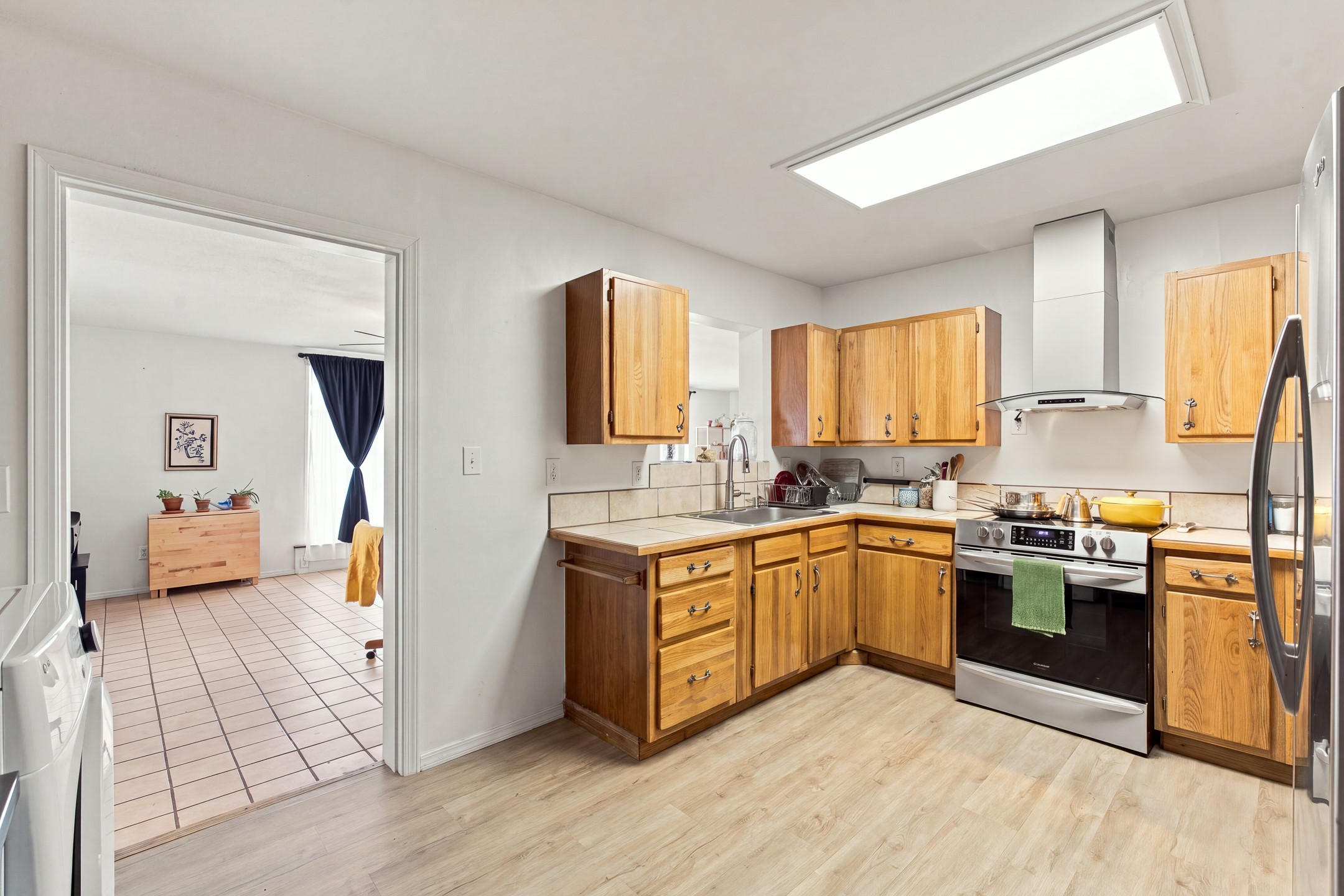 Kitchen with honey-colored wood cabinets, stainless-steel appliances, and a doorway to the laundry room.