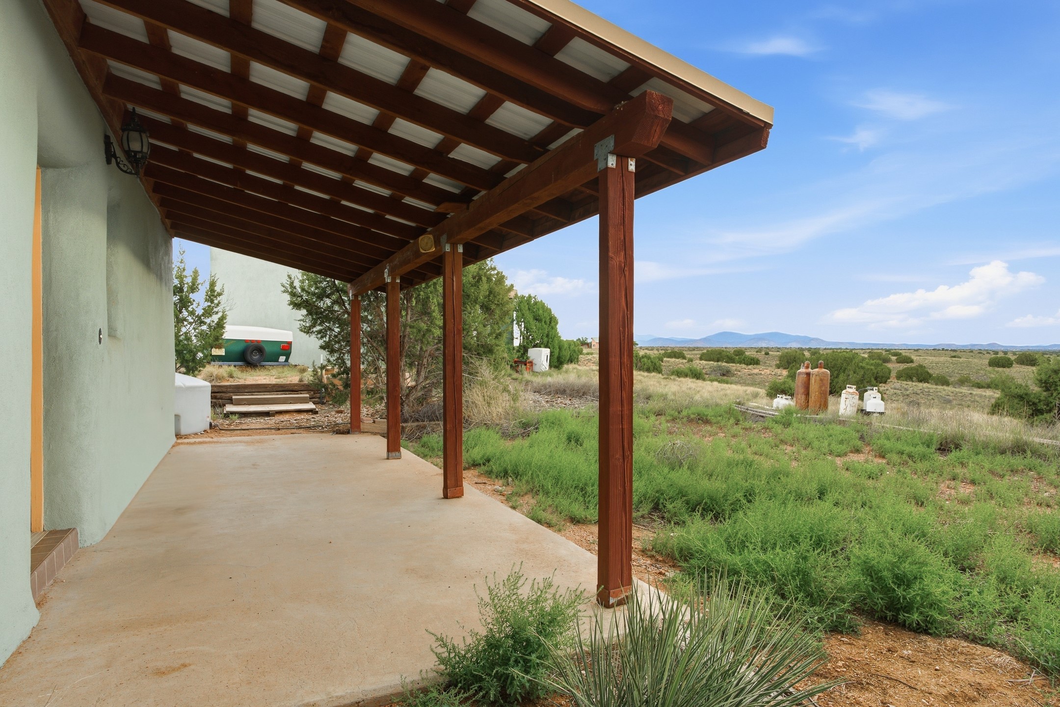 Covered patio with timber pergola overlooking scrubland and distant mountains.