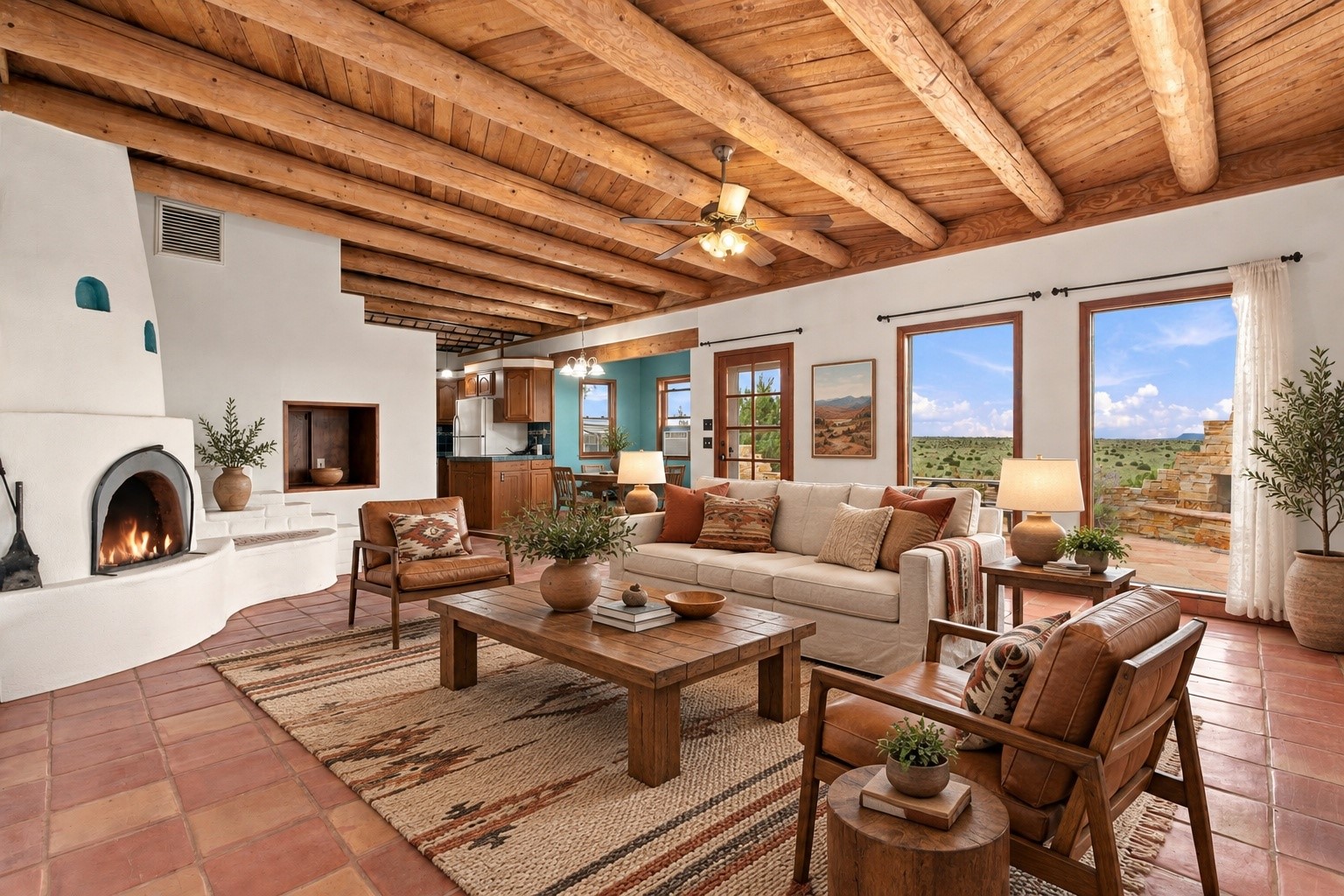 Living room with a kiva fireplace, exposed timber ceiling, leather seating, and views of the New Mexico landscape.