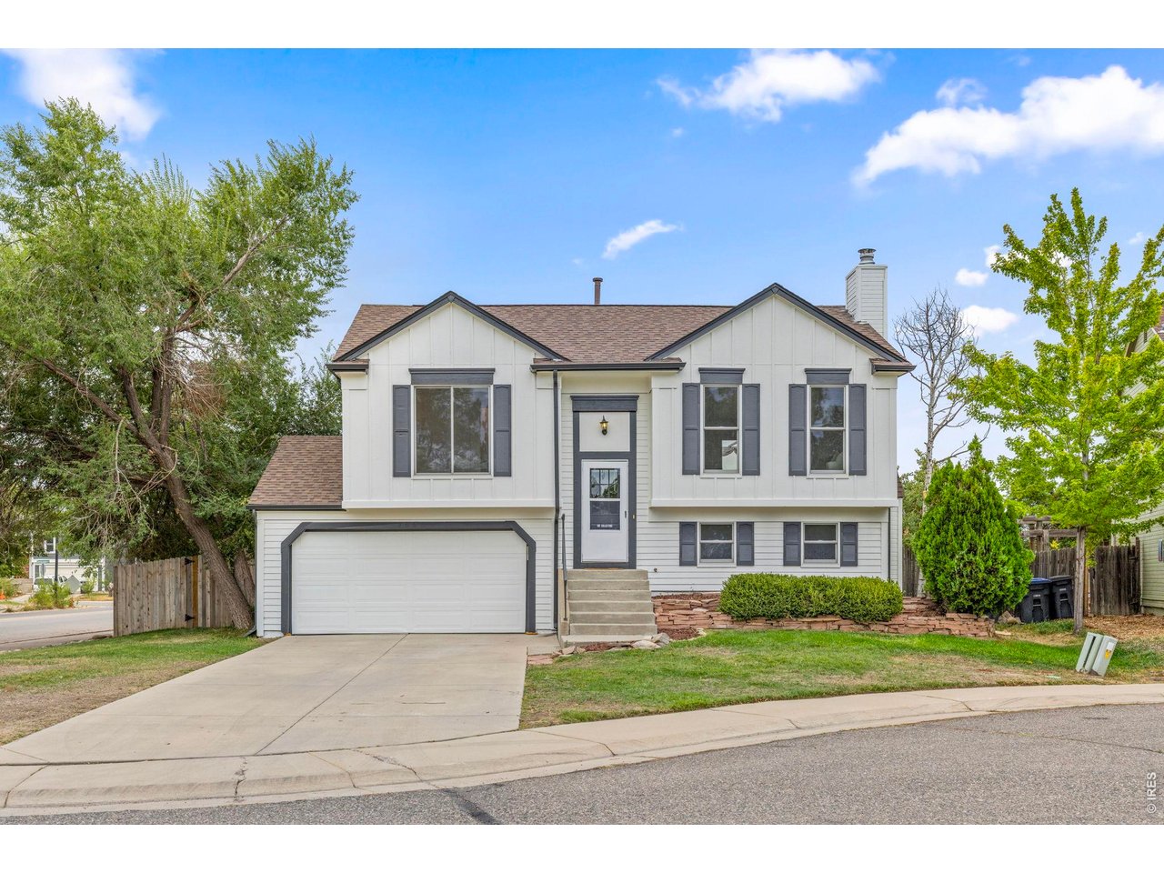 Two-story white house with gray shutters, a double garage, and a wide concrete driveway.
