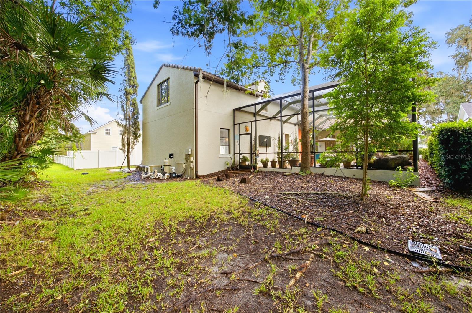 Rear of a two-story home with a screened patio and leafy backyard.