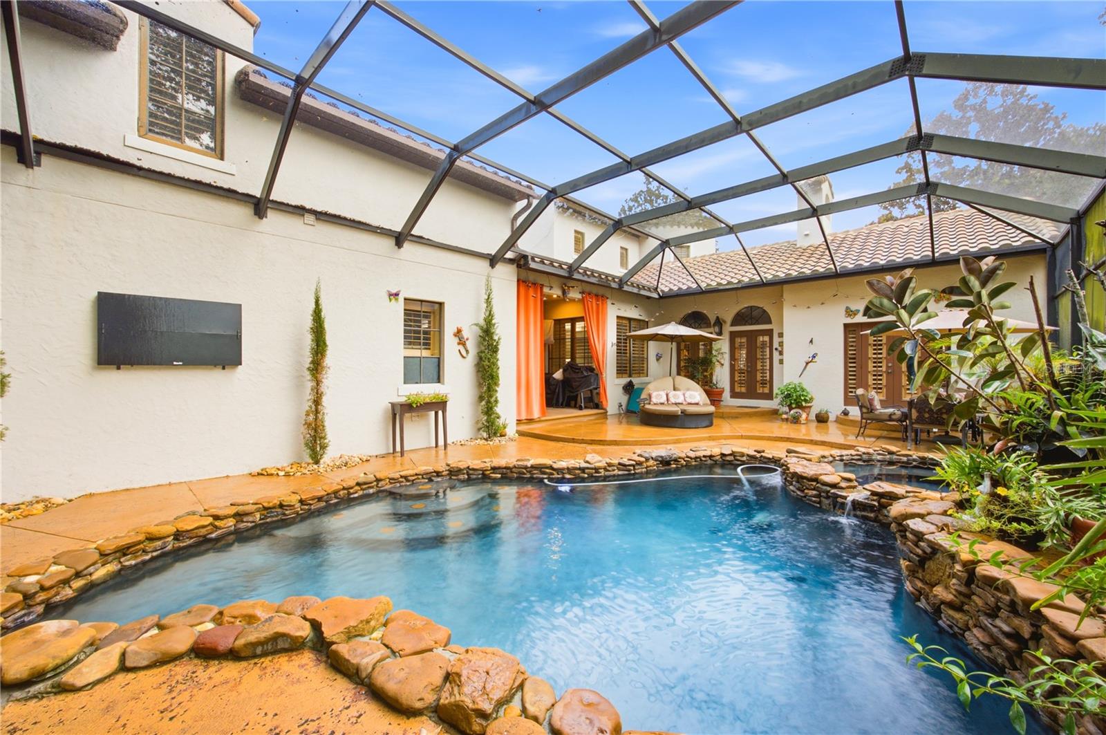 Backyard pool in a screened courtyard with stone edging and patio seating.