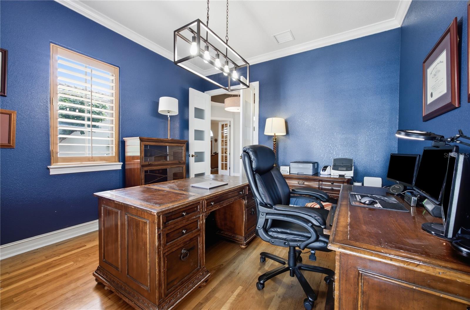 Home office with blue walls, hardwood floors, and ornate wooden desks.