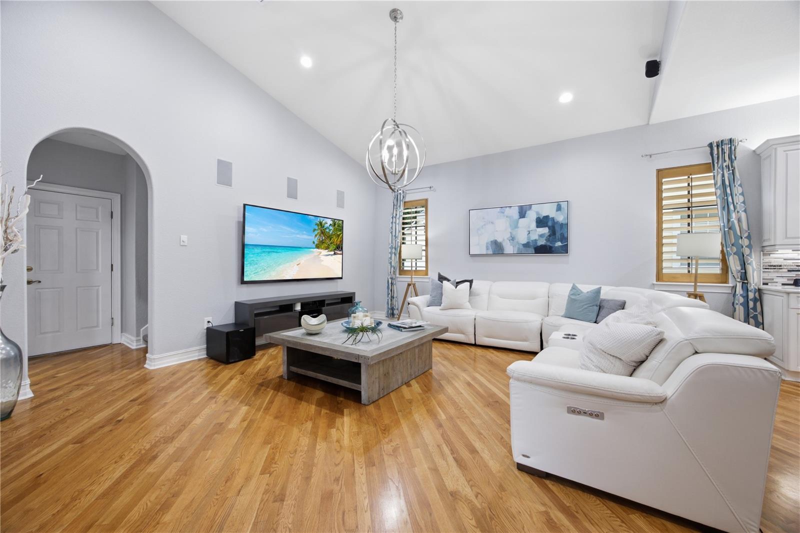 Living room with vaulted ceiling, hardwood floors, and a large white sectional sofa.