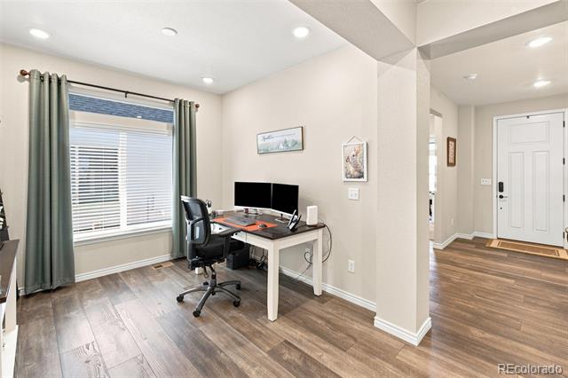 Home office with a desk and dual monitors beside a large curtained window.