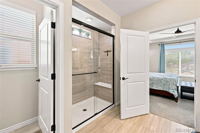 Bathroom with a black-framed glass shower and an open doorway to a bedroom.