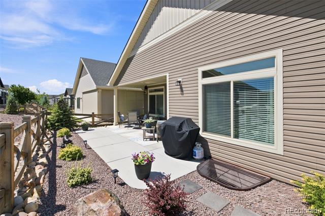 Concrete patio beside a beige-sided home, with outdoor seating and a covered grill.