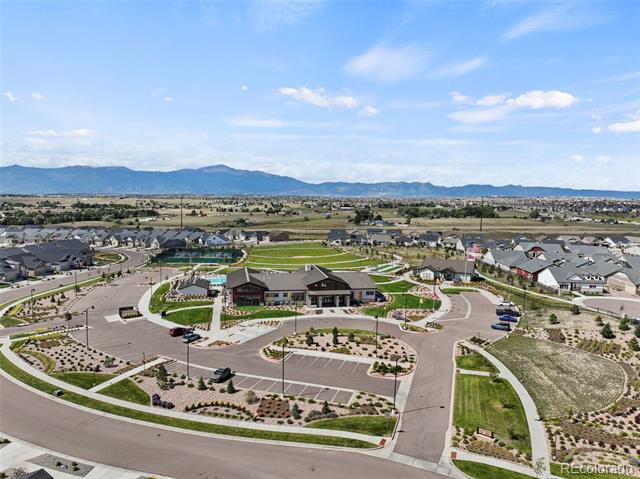 Aerial view of a residential community with a central clubhouse and mountains beyond.
