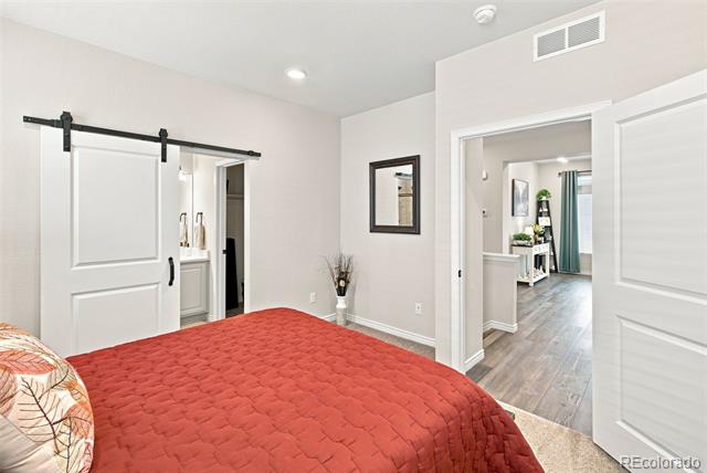 Bedroom with a red quilted bedspread and white sliding barn door.