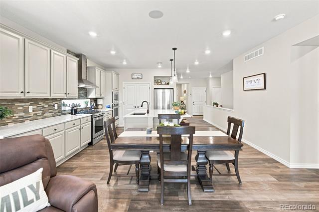 Open-plan kitchen and dining area with a large island, white cabinets, and dark wood table.