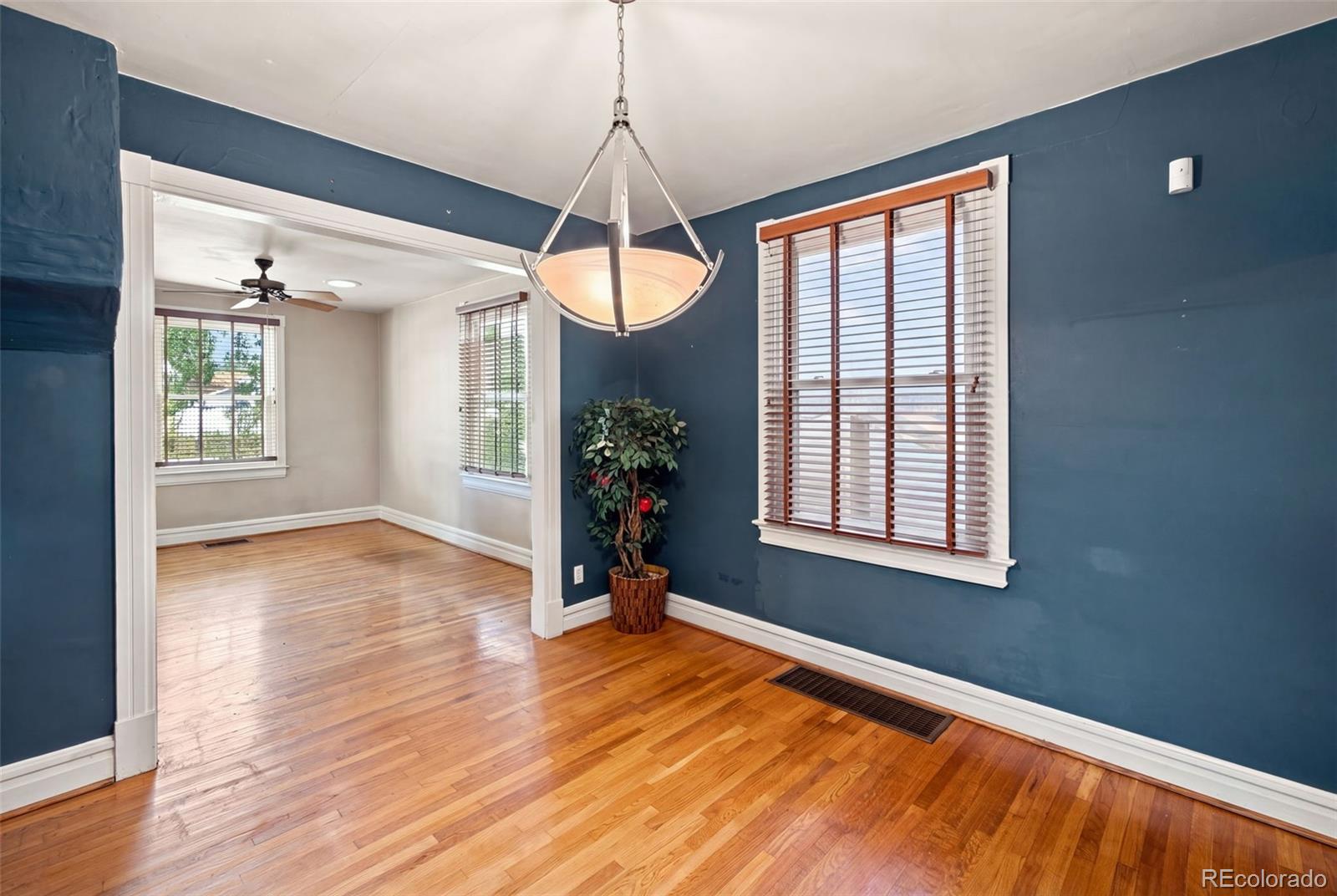 Dining room with blue walls, hardwood floors, and a chandelier beside an adjoining room.