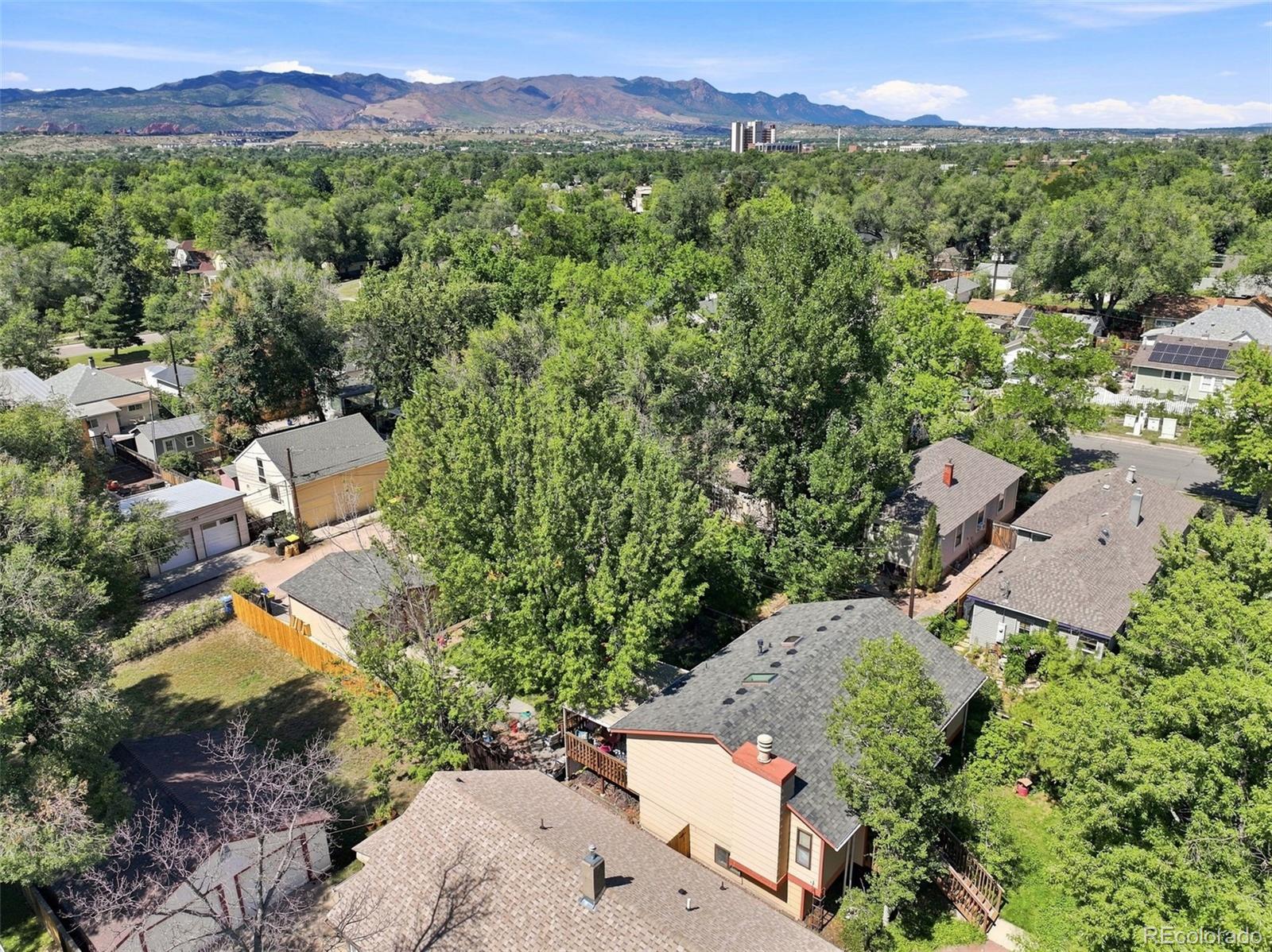 Aerial view of a leafy Colorado Springs neighborhood with the Rocky Mountains on the horizon.