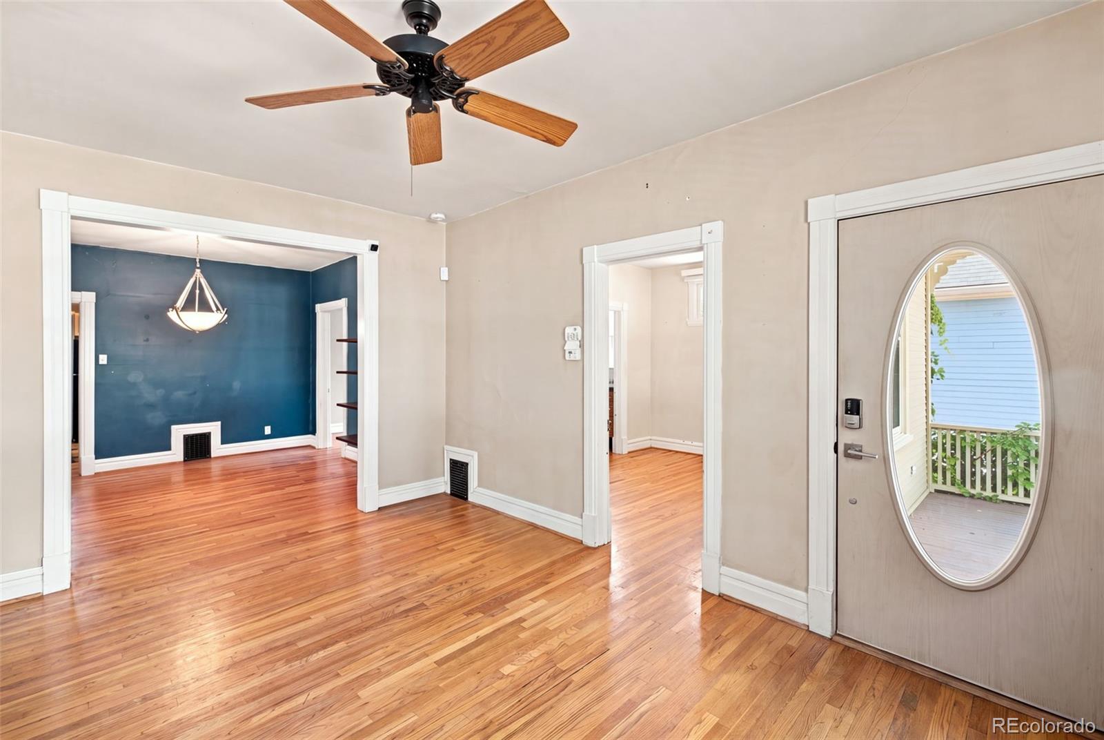 Entryway with polished hardwood floors, a ceiling fan, and an oval-glass front door.