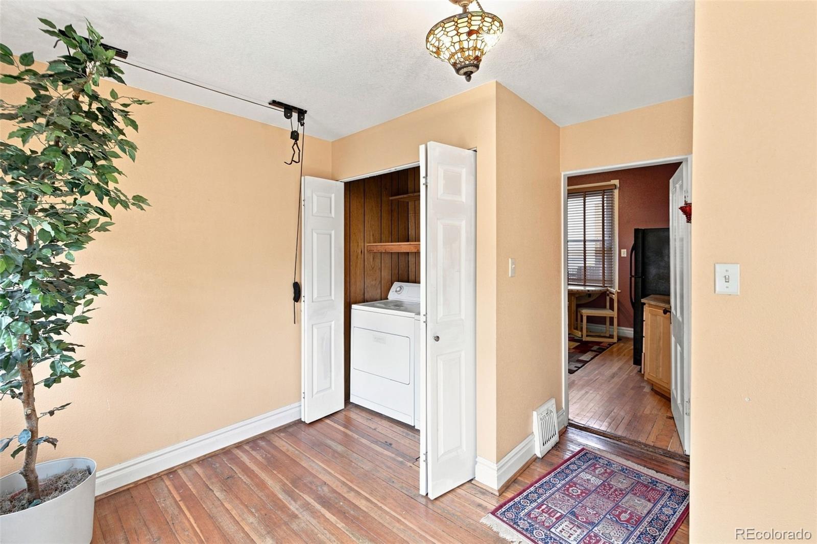 Laundry area with washer and dryer in a wood-paneled closet and hardwood floors.