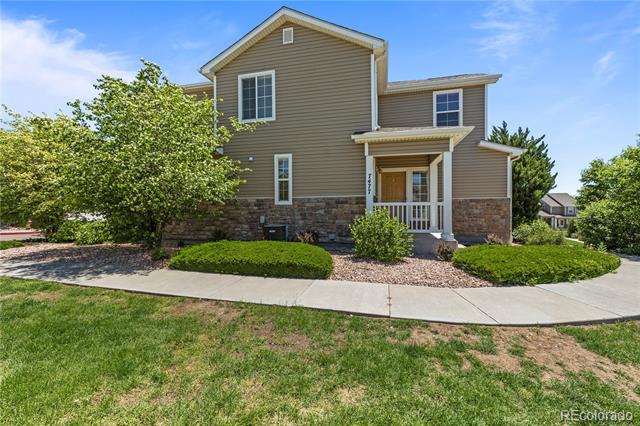 Two-story taupe home with stone veneer, a covered porch, and landscaped front yard.