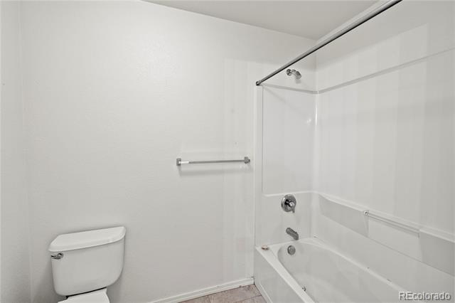 Bathroom with a white toilet beside a bathtub and glass-enclosed shower.