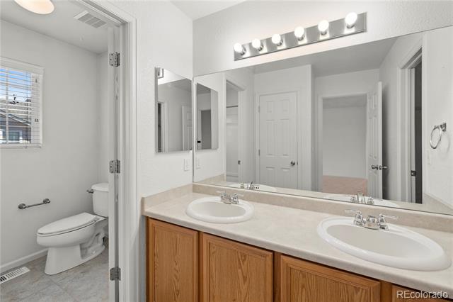 Bathroom with a double-sink vanity and a toilet alcove with a window.