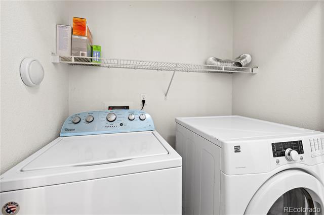 Laundry room with a top-loading washer, front-loading dryer, and wire shelf.