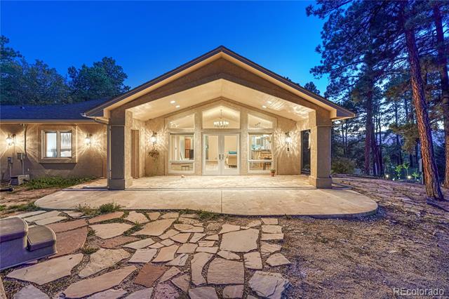 Single-story home with a brightly lit covered entry and flagstone walkway at dusk.