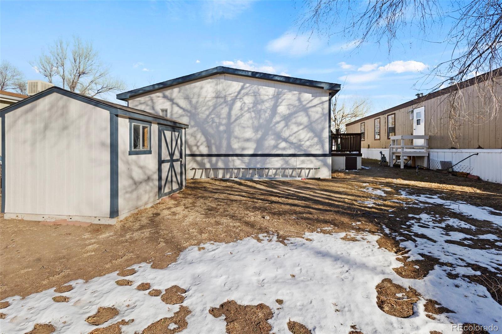 Backyard with a large outbuilding, barn-style shed, and patches of snow.