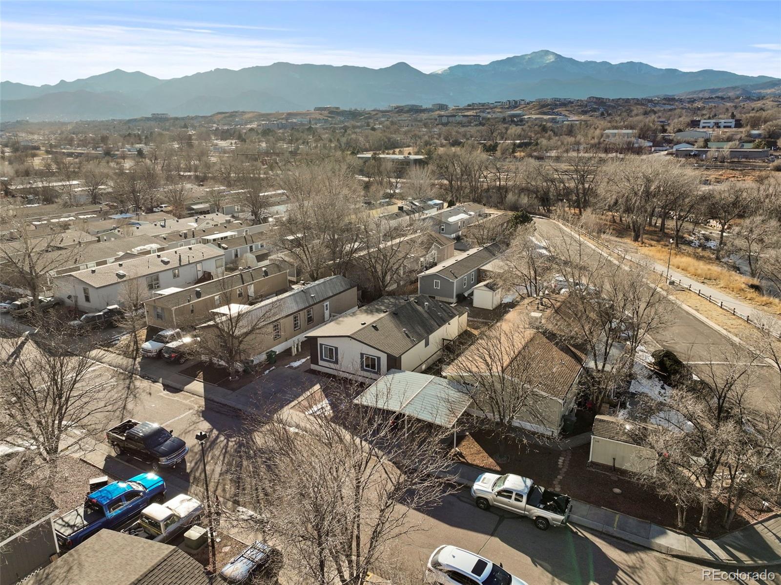 Aerial view of homes and leafless trees with a mountain range in the distance.
